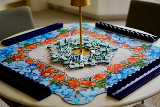 A mahjong table featuring a an original painting mahjong mat with tiles, racks and a mahjong table lamp