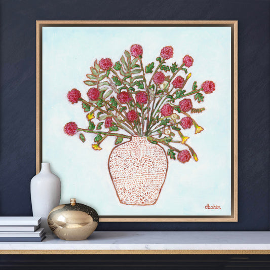 Framed artwork of a red dahlia floral arrangement on a light blue background, with a white patterned vase and plants on a wooden surface.