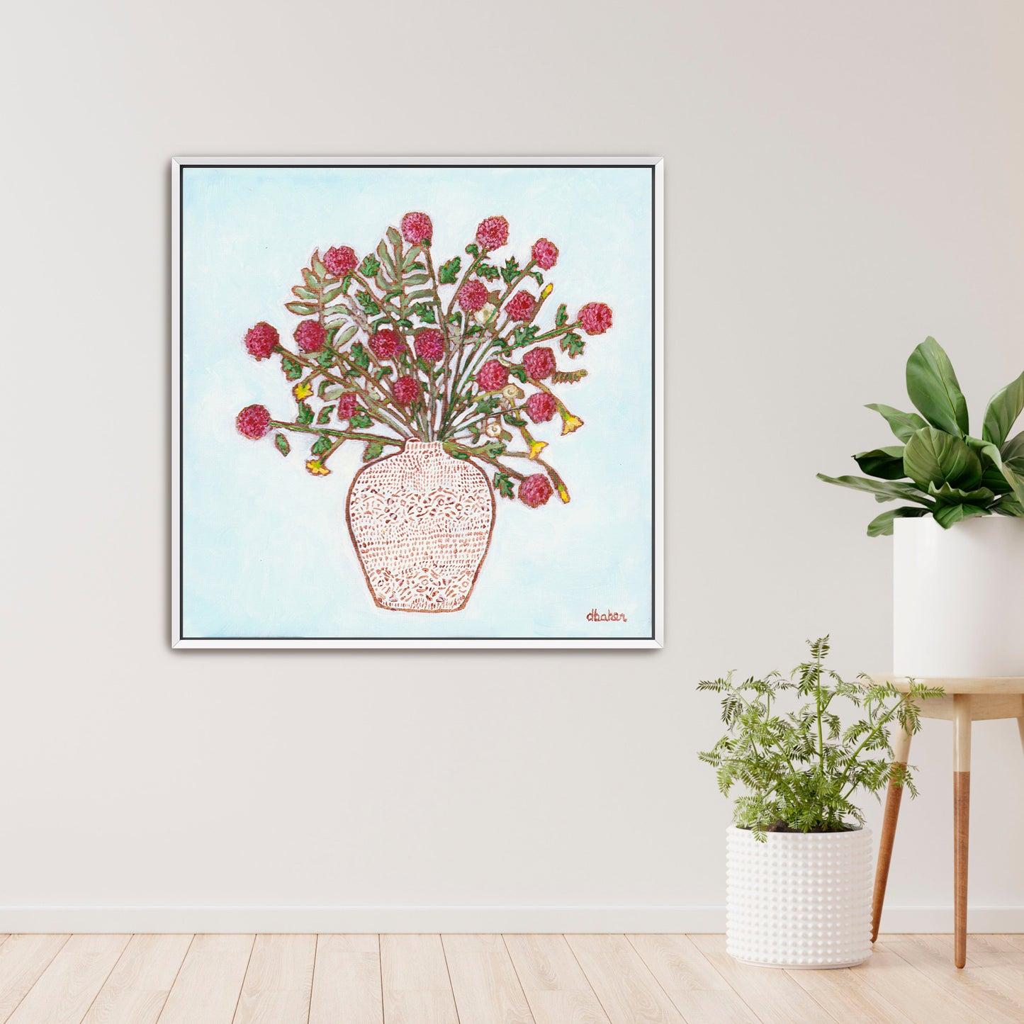 Framed artwork of a red dahlia floral arrangement on a light blue background, with a white patterned vase and plants on a wooden surface.