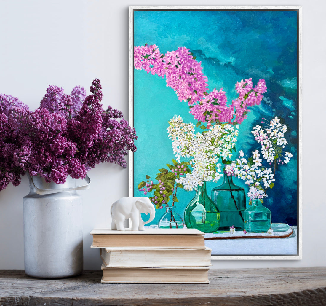 Decorative setup with a vase of purple flowers, books, and a framed painting of lilacs from Trail East Studio in Ada Michigan.