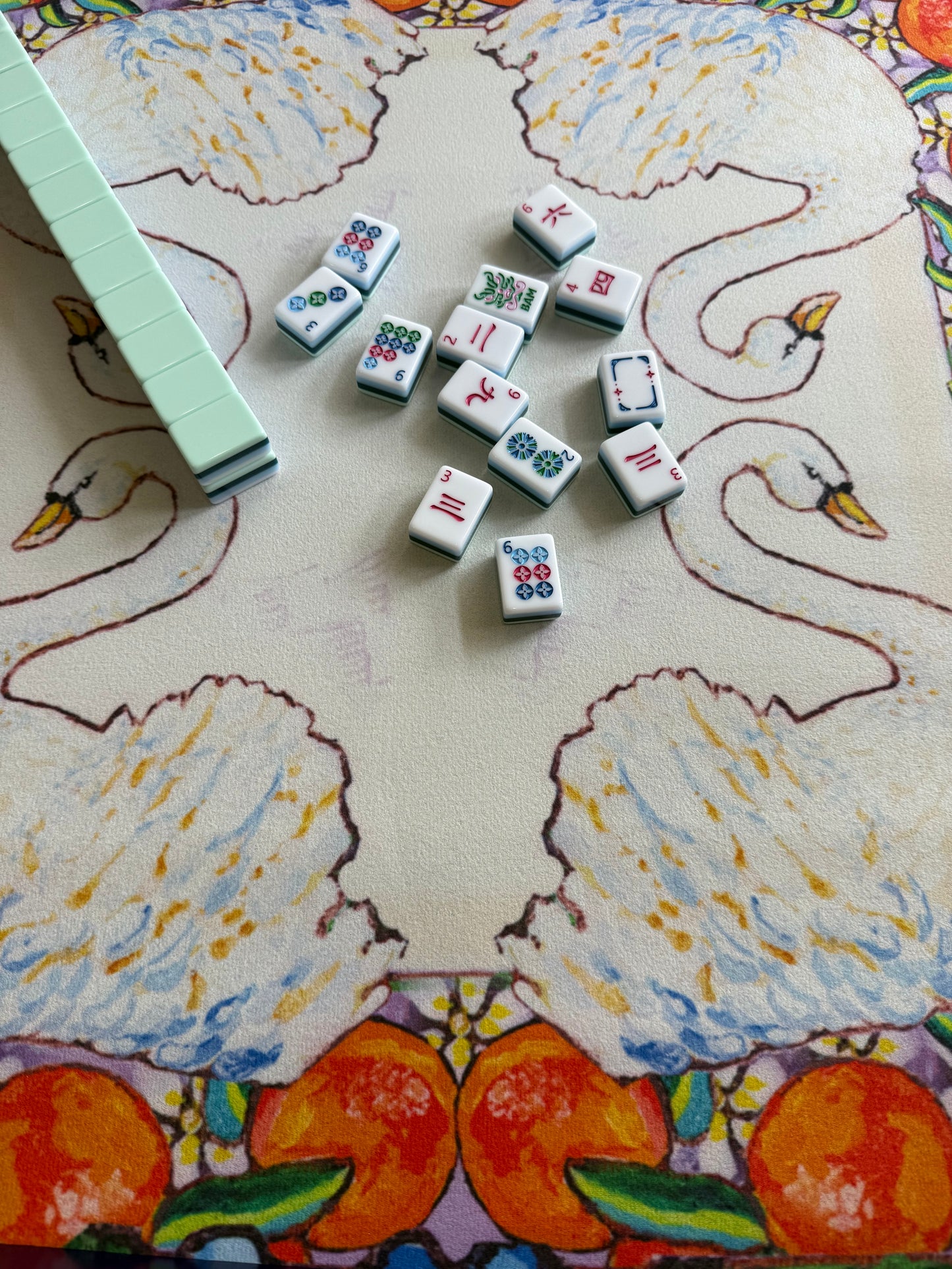 A colorful mahjong mat featuring an original painting of swans, oranges, orange blossoms and hydrangeas.