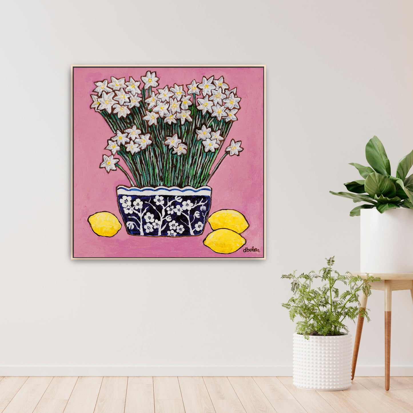 A whimsical painting of paperwhites in a blue and white floral vase surrounded by lemons against a bright pink background.
