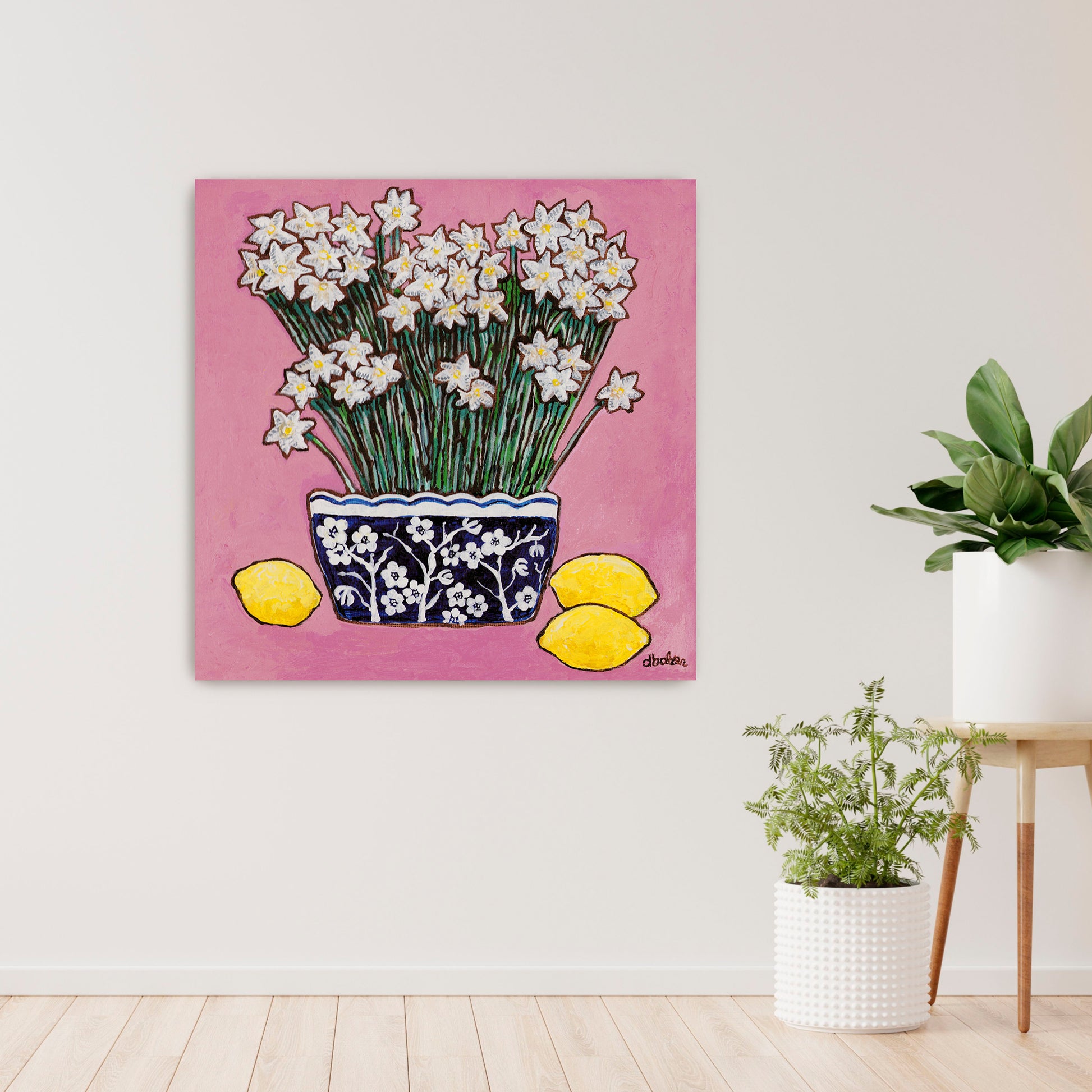 A whimsical painting of paperwhites in a blue and white floral vase surrounded by lemons against a bright pink background.