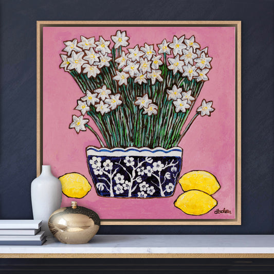 A whimsical painting of paperwhites in a blue and white floral vase surrounded by lemons against a bright pink background.