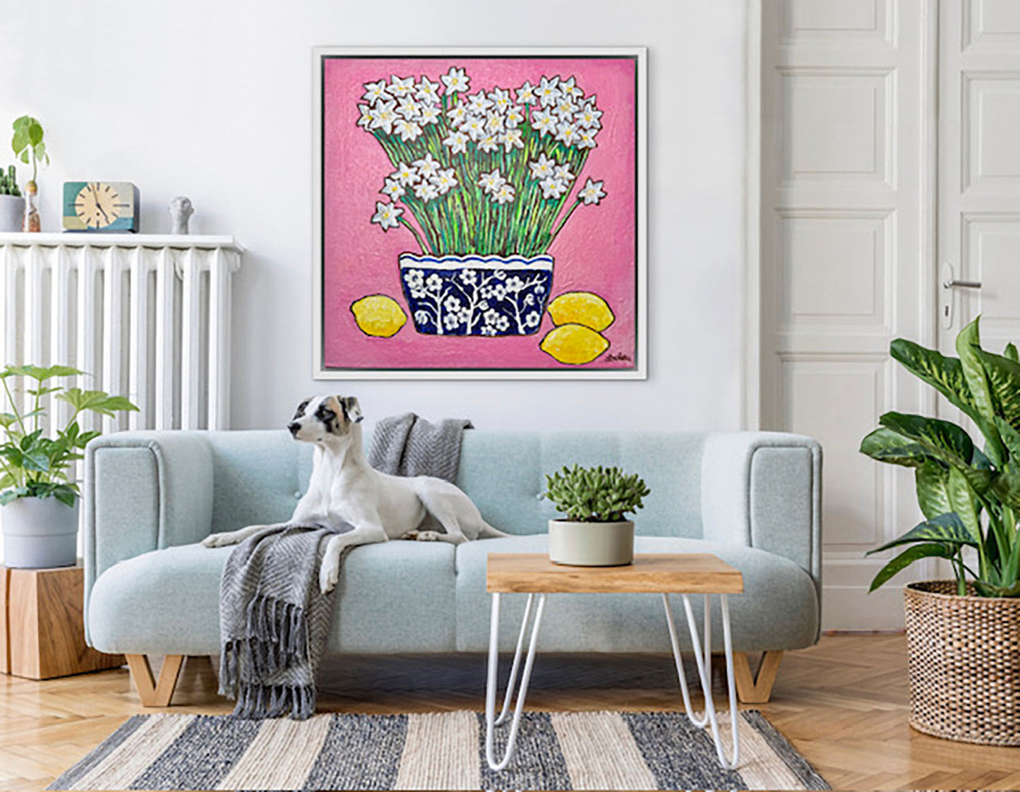 A whimsical painting of paperwhites in a blue and white floral vase surrounded by lemons against a bright pink background.