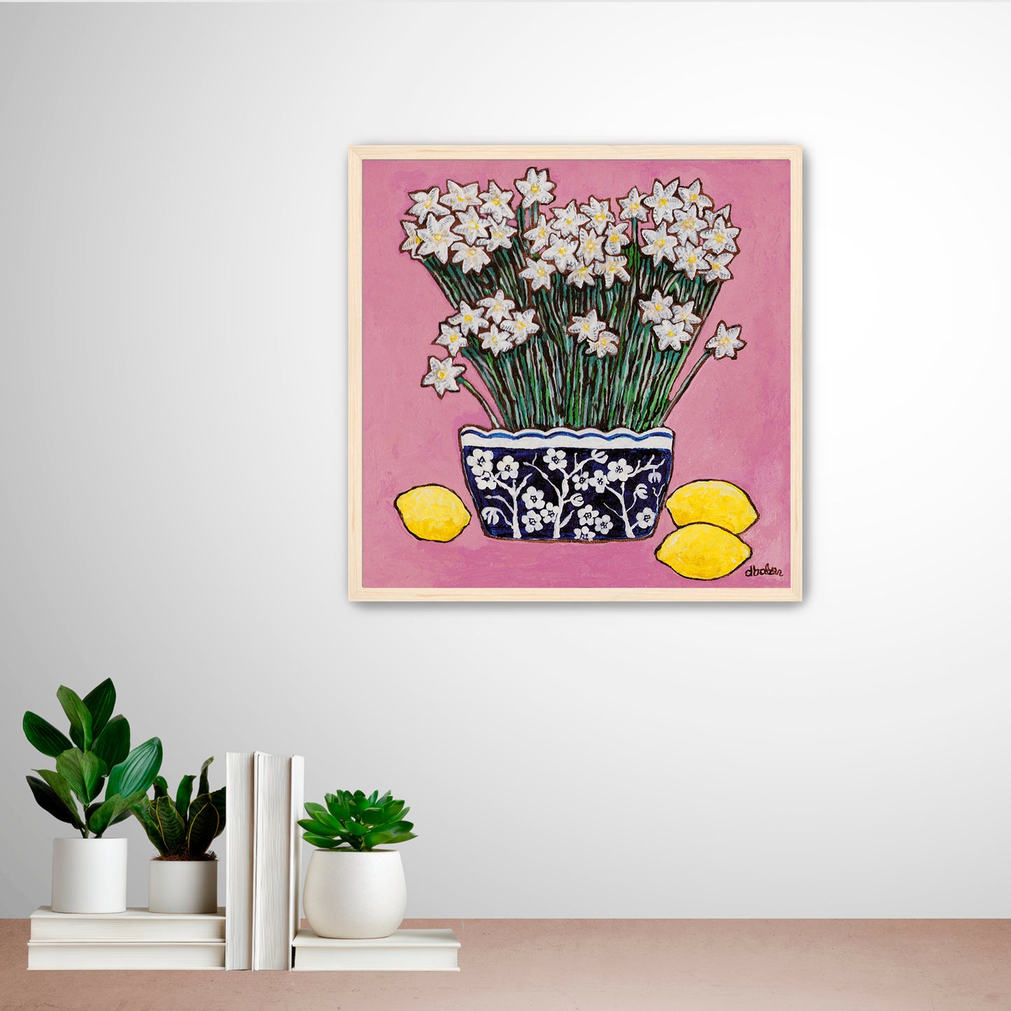A whimsical painting of paperwhites in a blue and white floral vase surrounded by lemons against a bright pink background.
