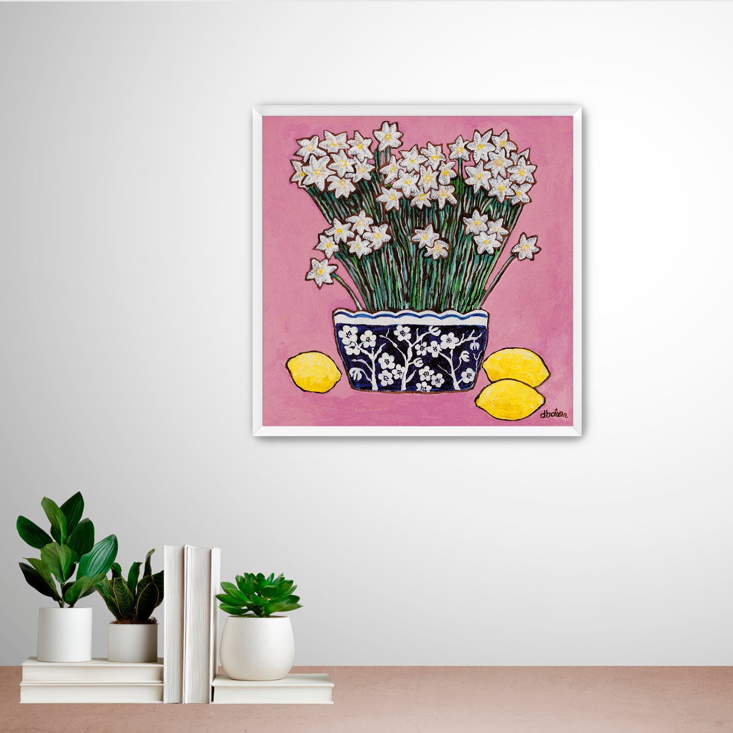 A whimsical painting of paperwhites in a blue and white floral vase surrounded by lemons against a bright pink background.
