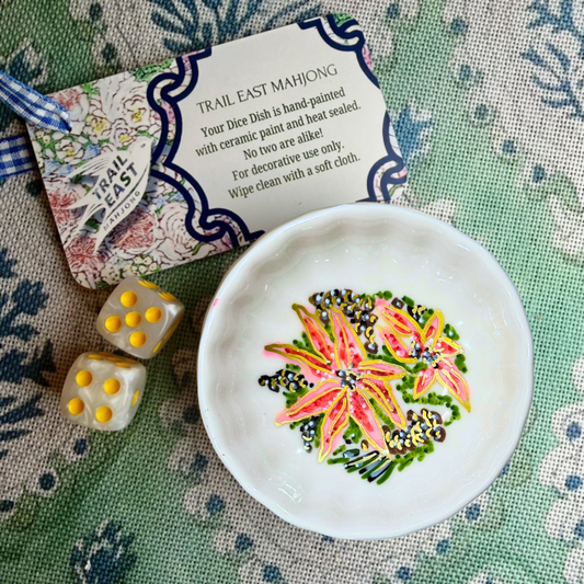A hand painted mahjong dice dish featuring pink and red poinsettia flowers and pine cones from Trail East Studio in Ada Michigan