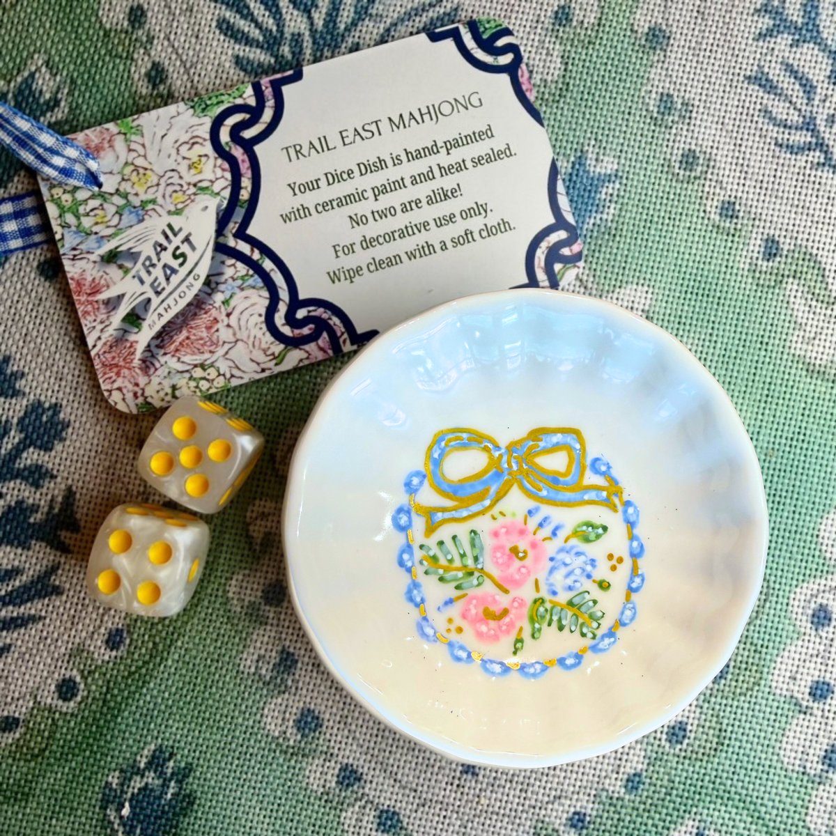 A hand painted mahjong dice dish from Trail East Studio in Ada Michigan featuring a bow and flowers. The perfect hostess gift!
