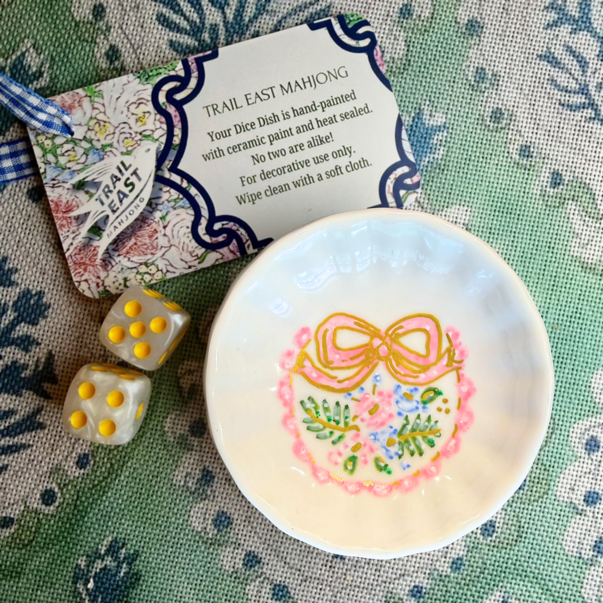 A hand painted mahjong dice dish from Trail East Studio in Ada Michigan featuring a bow and flowers. The perfect hostess gift!